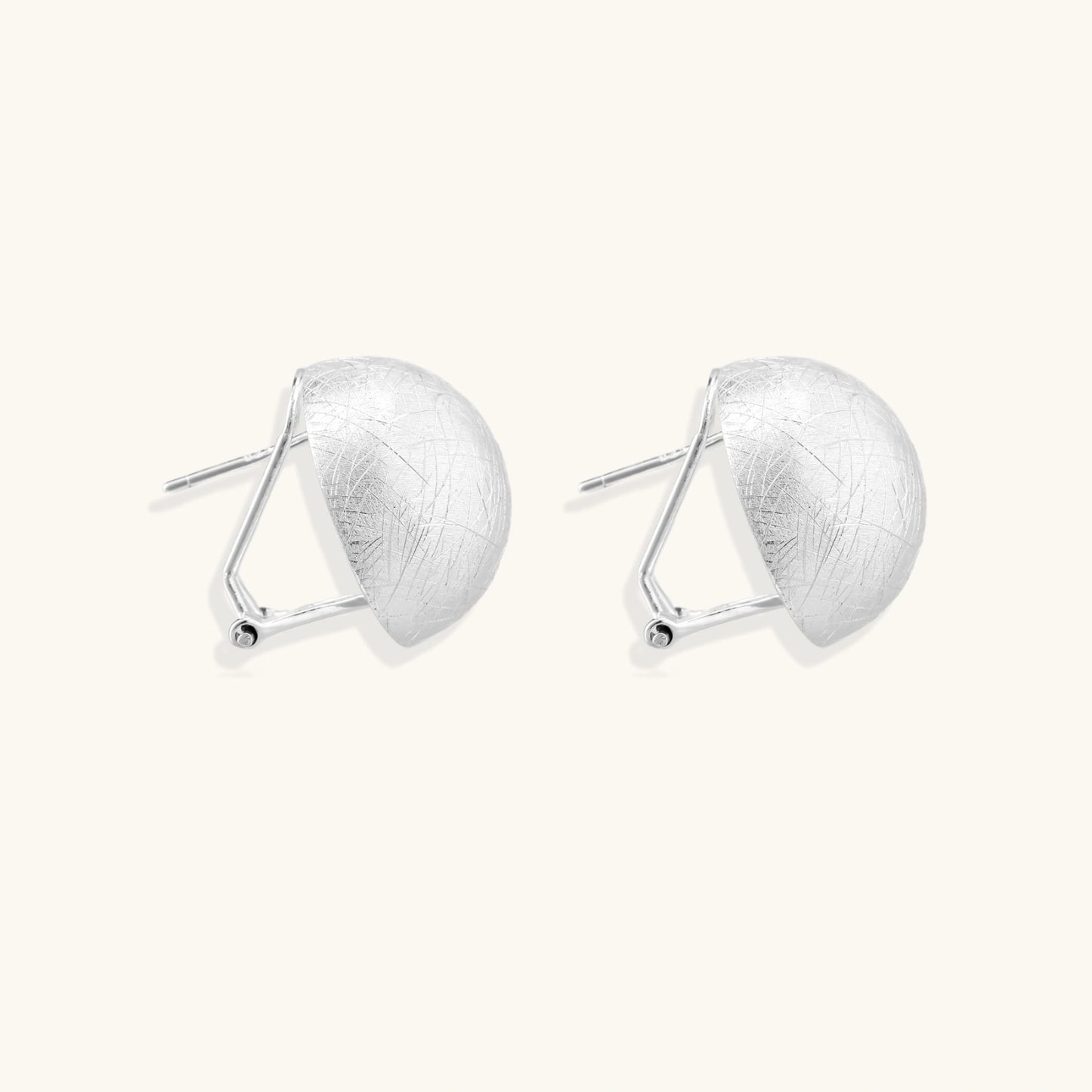 Brushed sterling silver half-dome clip-on earrings with textured surface against cream background